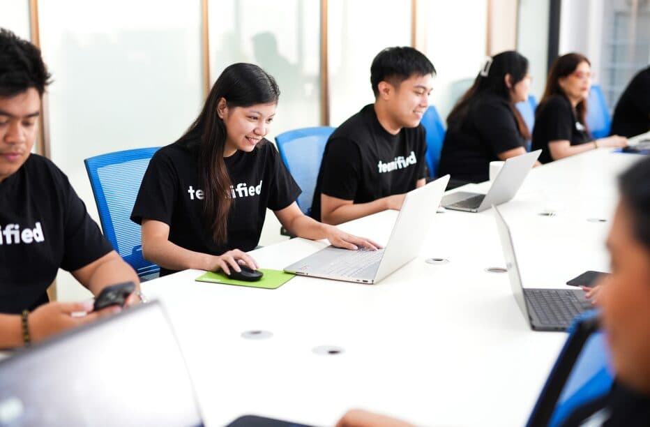 Teamified team members working on laptops in a bright Manila office