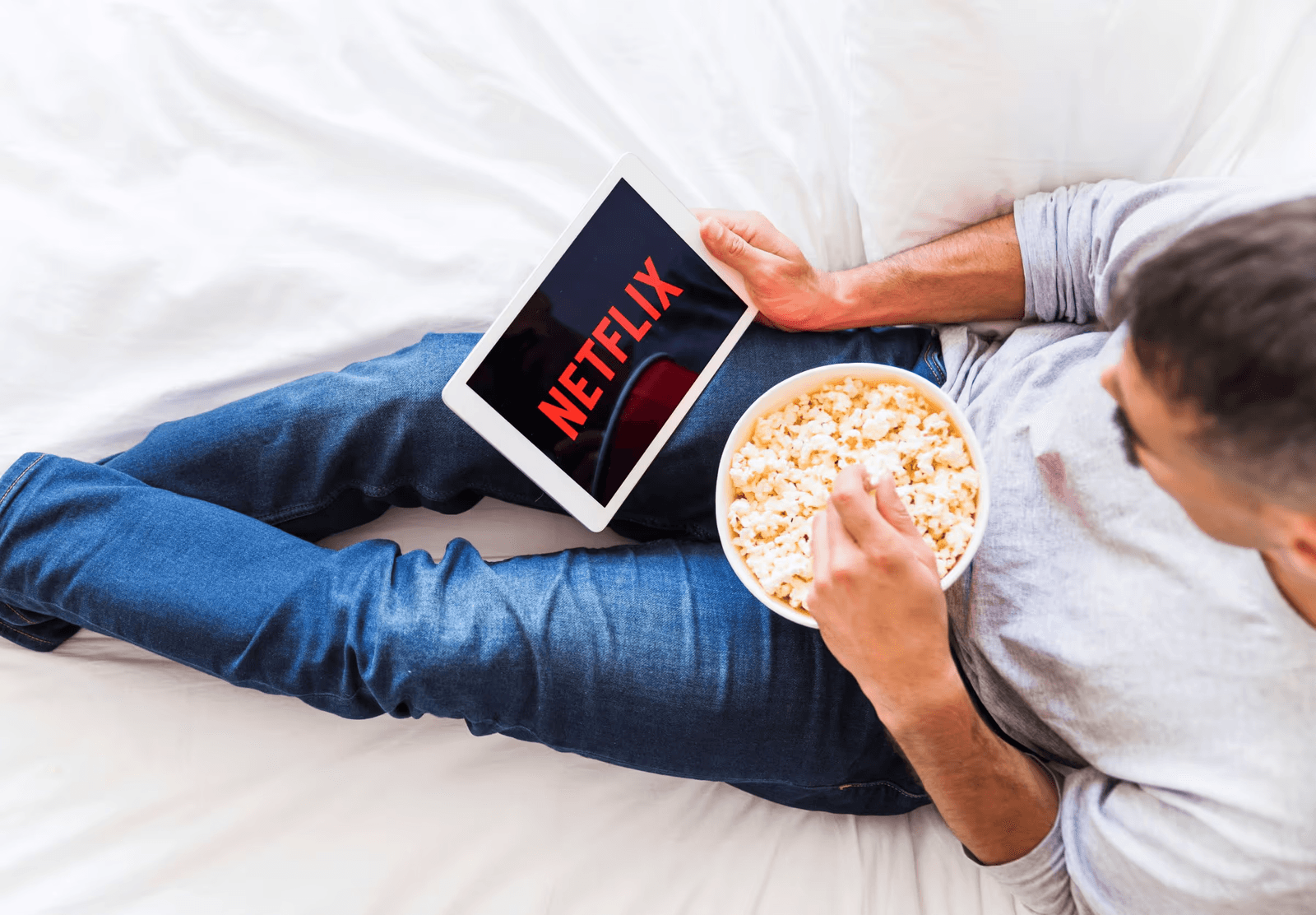 Man relaxing with popcorn while streaming Netflix on a tablet