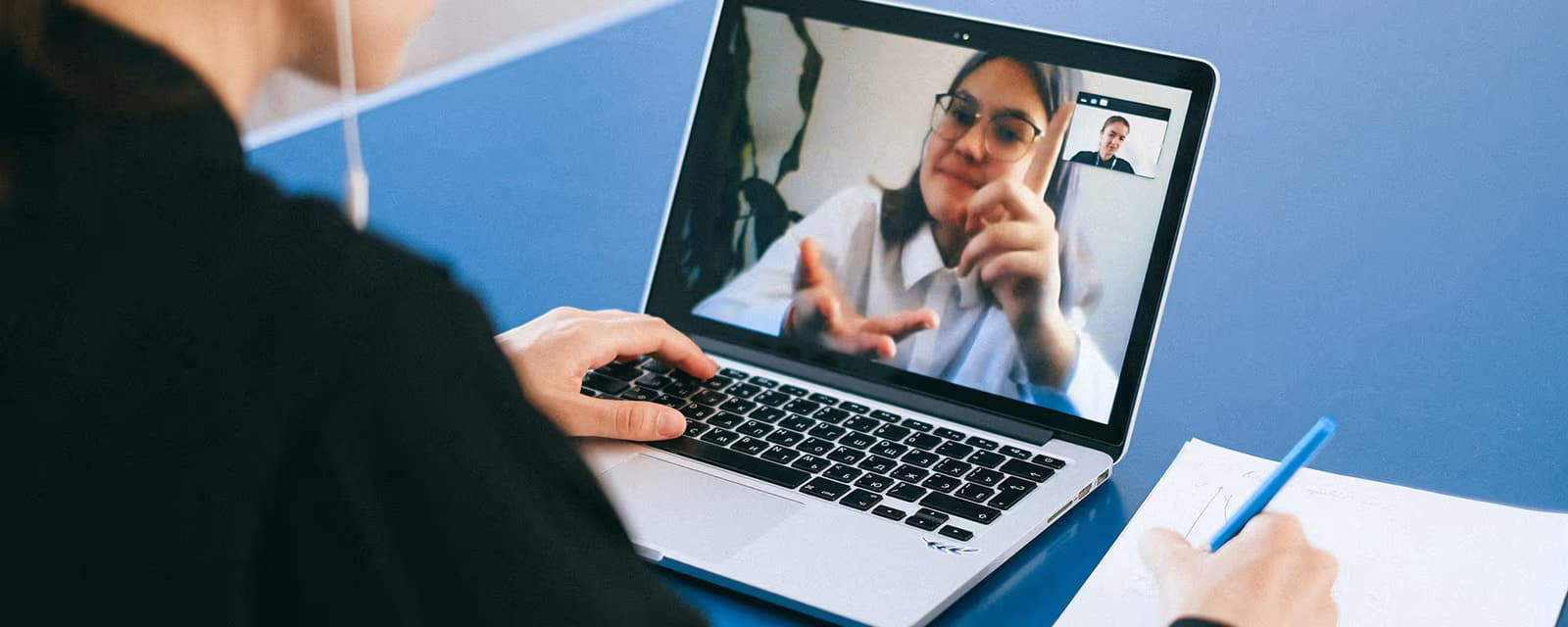 Team member taking notes during a video call with a remote colleague